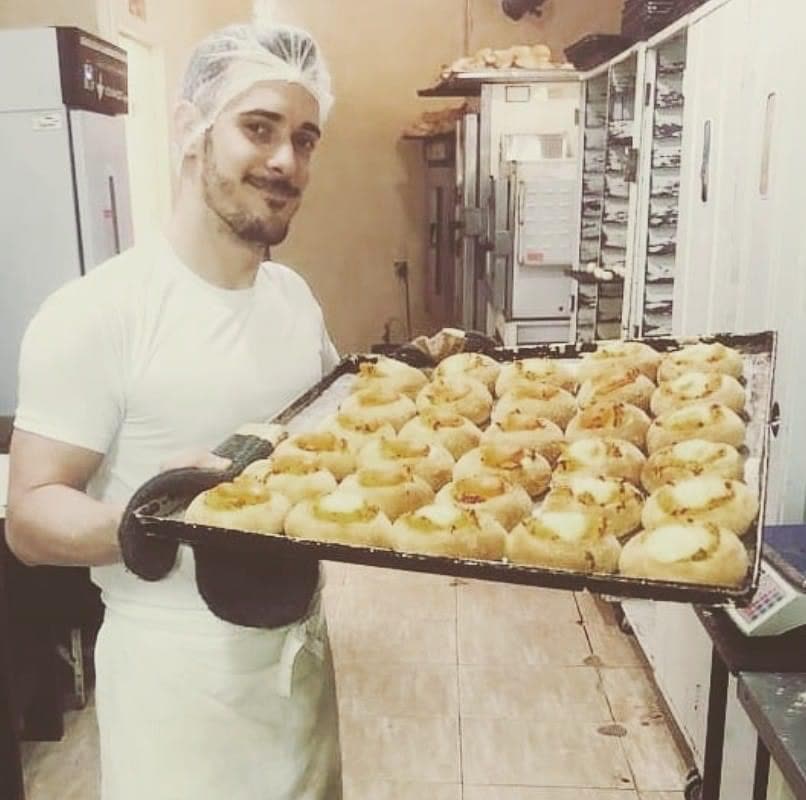 Renato de touca, segurando uma assadeira cheia de pães