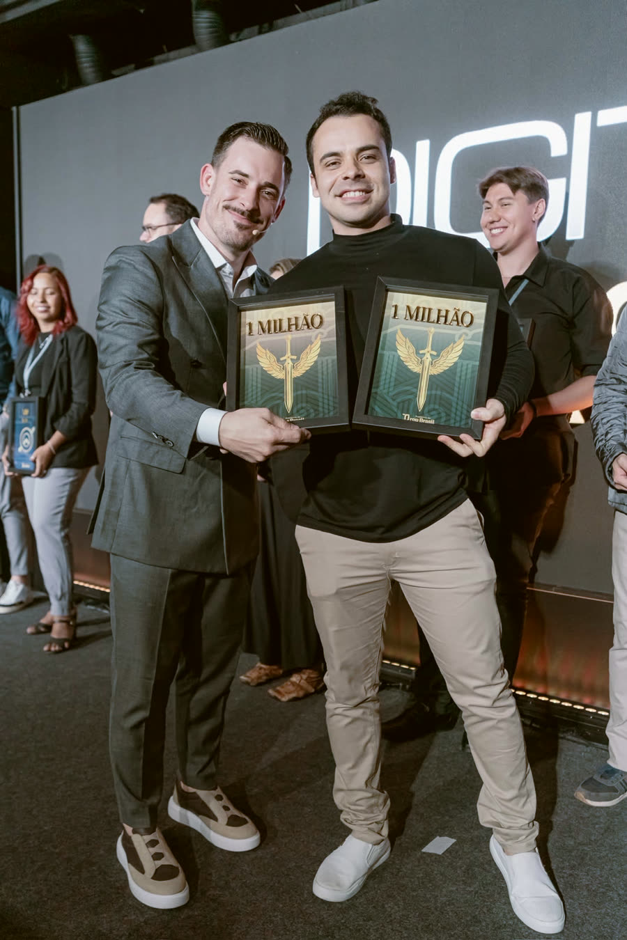 Renato e aluno no palco, cada um segurando uma placa de 1 milhão