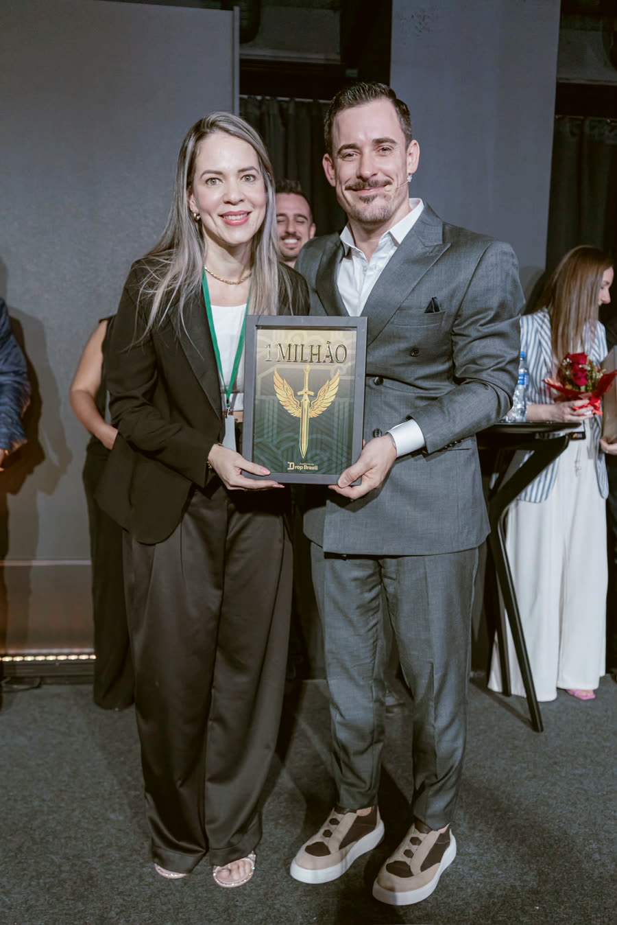 Aluna com a placa de faturamento ao lado do Renato