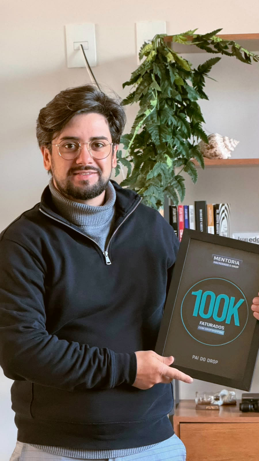 Aluno em casa segurando a placa de 100 mil faturados