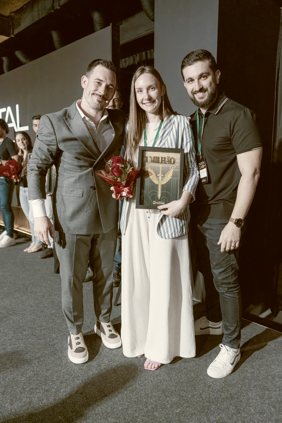 Aluna com flores e a placa, ao lado do Renato