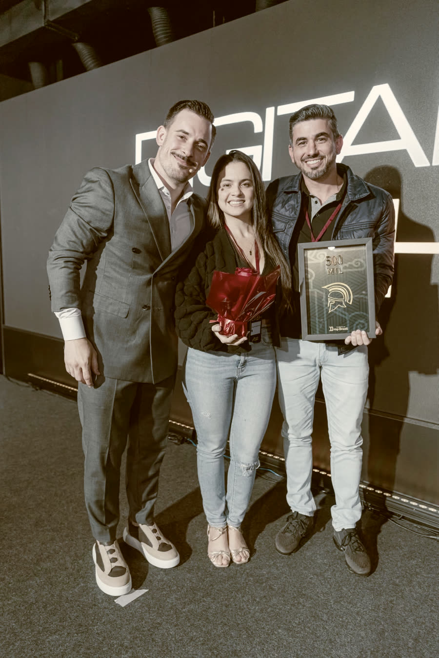 Aluna com a placa de faturamento ao lado do Renato
