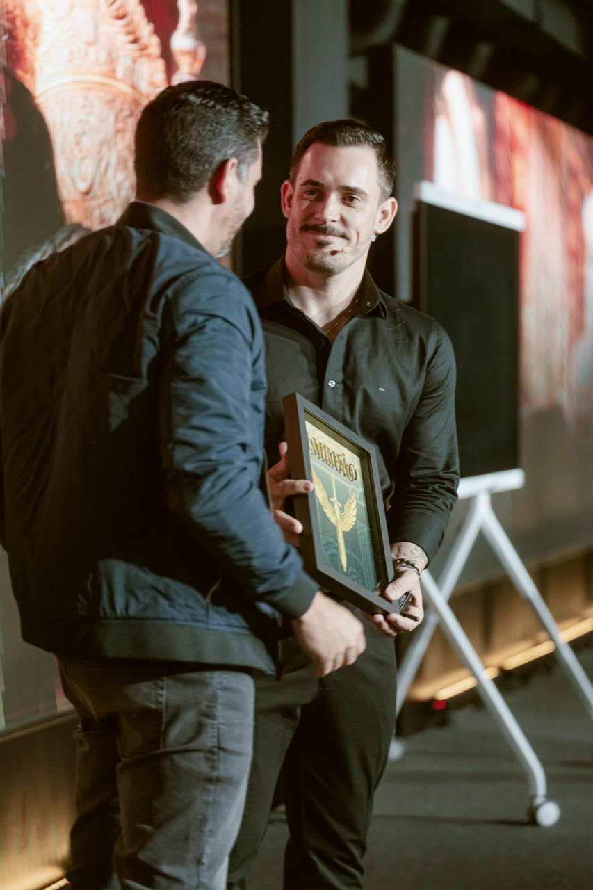 Aluno recebendo a placa no palco