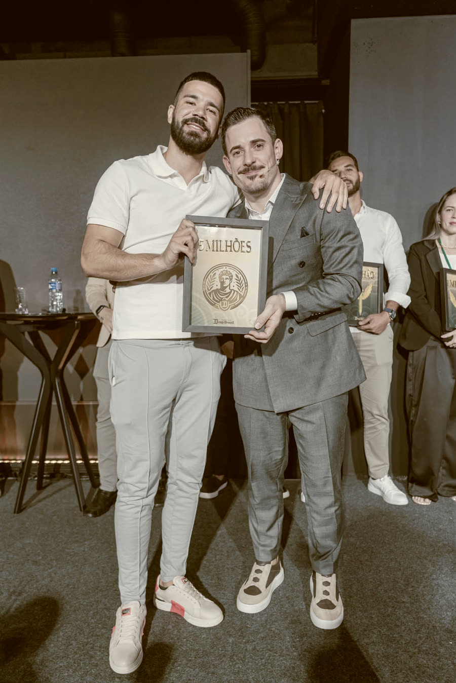 Aluno com a placa de faturamento ao lado do Renato