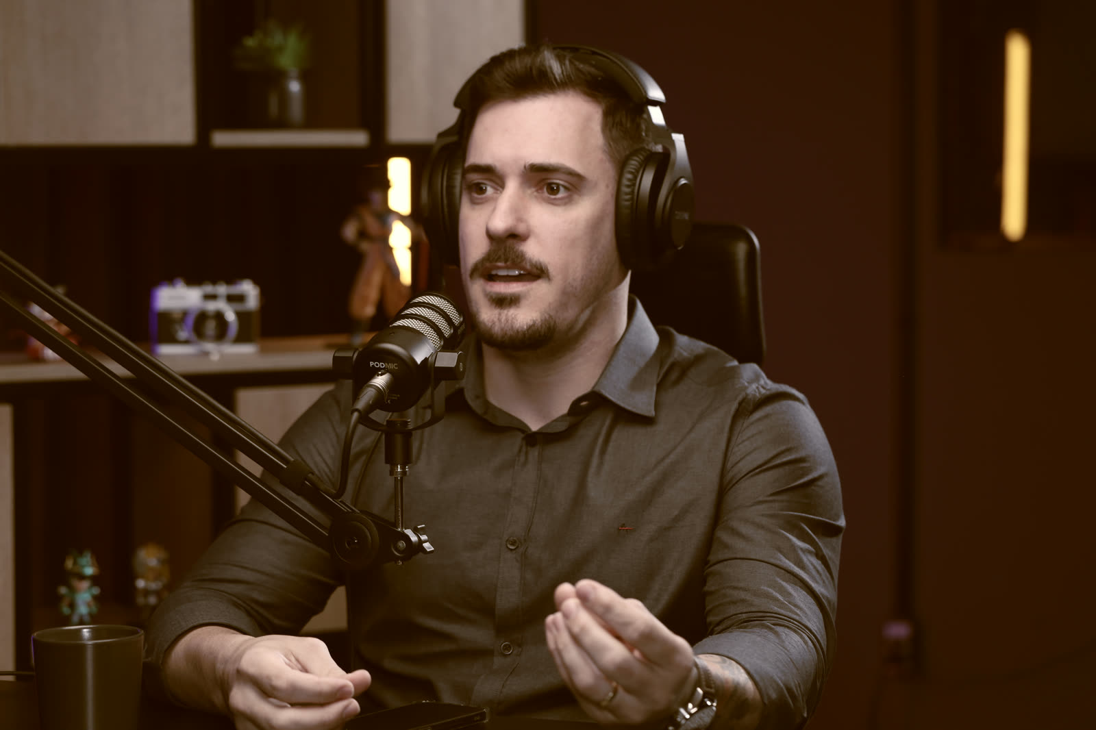 Renato num estúdio de podcast, de fone de ouvido, falando ao microfone